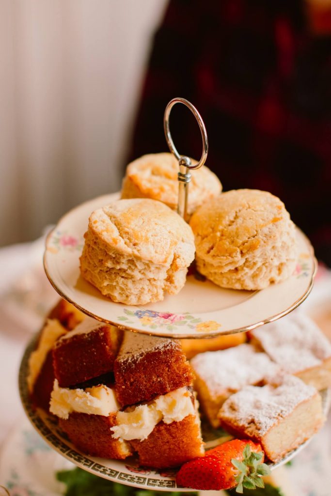 large vintage cake stand filled with cake, scones and fruit for afternoon tea